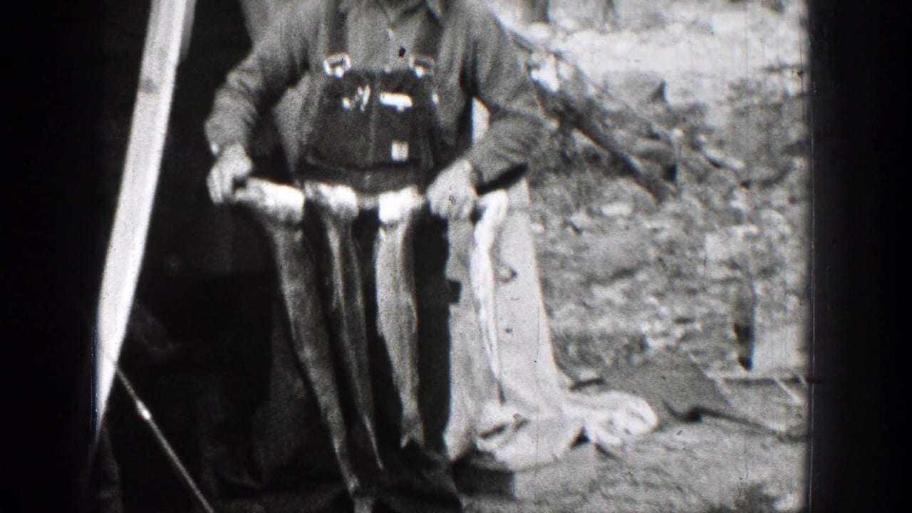 Two adult fishermen in Chelan, Washington, stand in work clothes and hats while displaying their catch on 1939 8mm film.