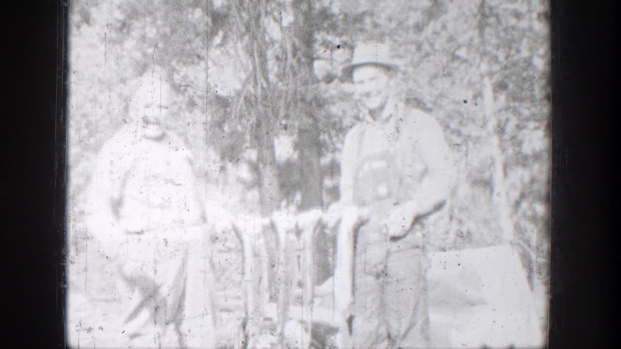 One fisherman smiles toward the camera while standing with another person and several fish in a wooded Chelan setting.