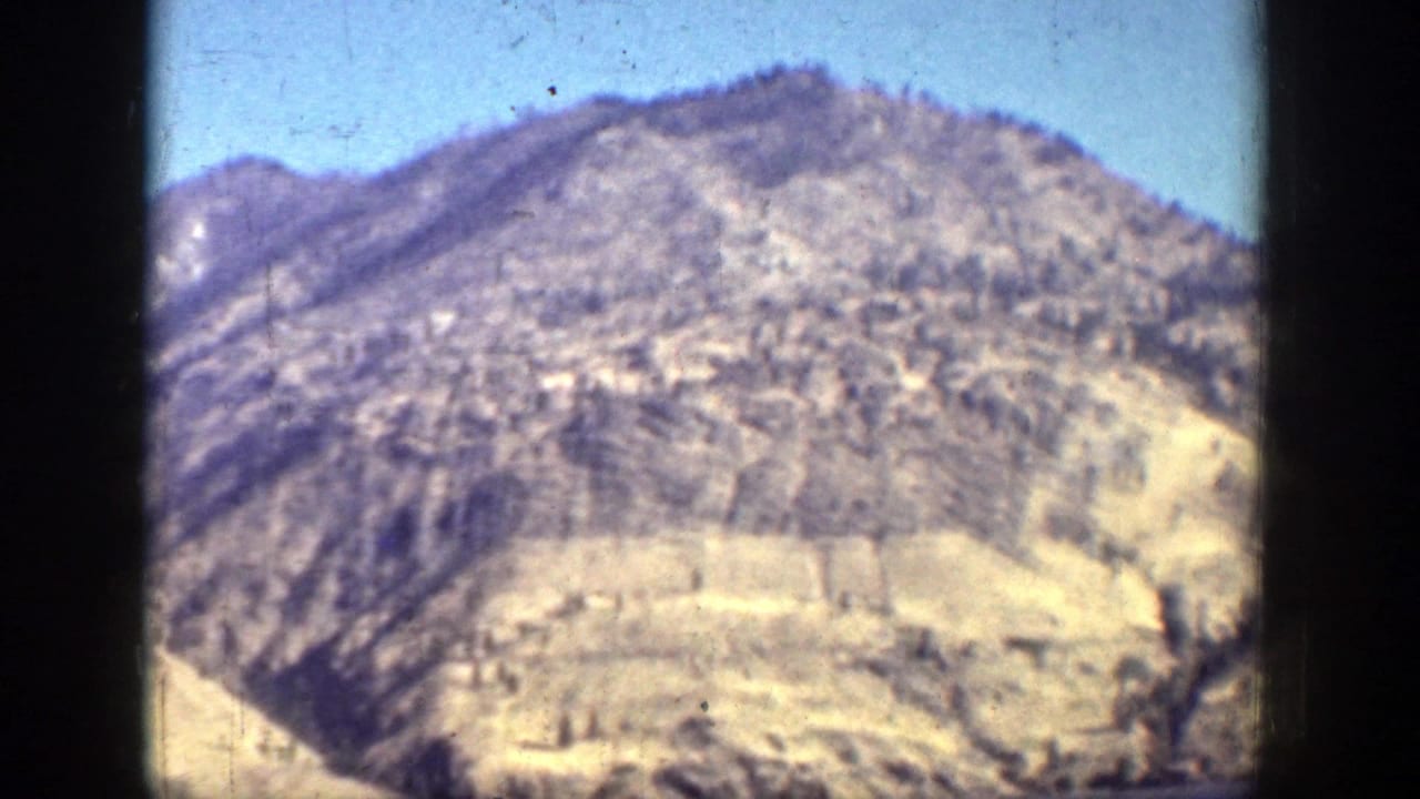 The camera holds on a rugged, dry mountain slope near Chelan, showing faded color, grain, and dust in the 8mm scan.