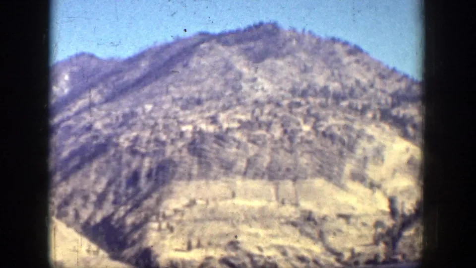 The camera holds on a rugged, dry mountain slope near Chelan, showing faded color, grain, and dust in the 8mm scan.
