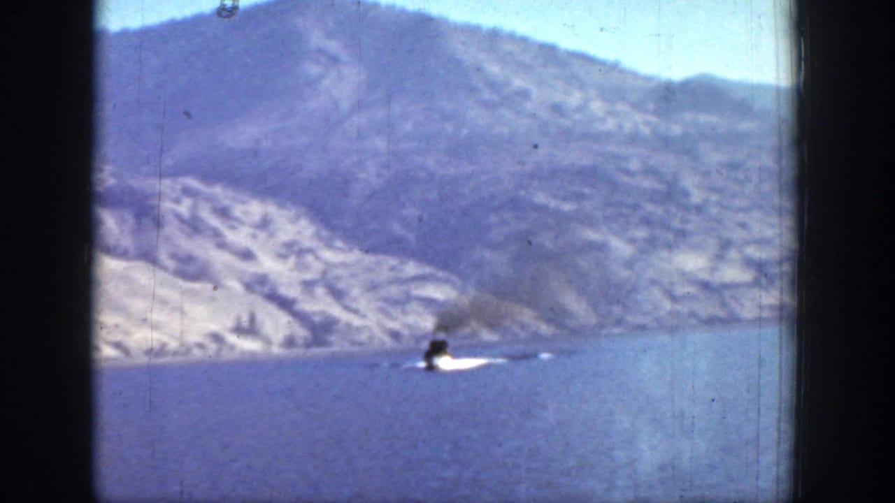 1939 Chelan, Washington home-movie frame showing a steamboat leaving a white wake on a mountain lake.