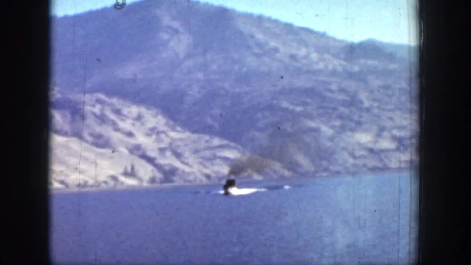1939 Chelan, Washington home-movie frame showing a steamboat leaving a white wake on a mountain lake.