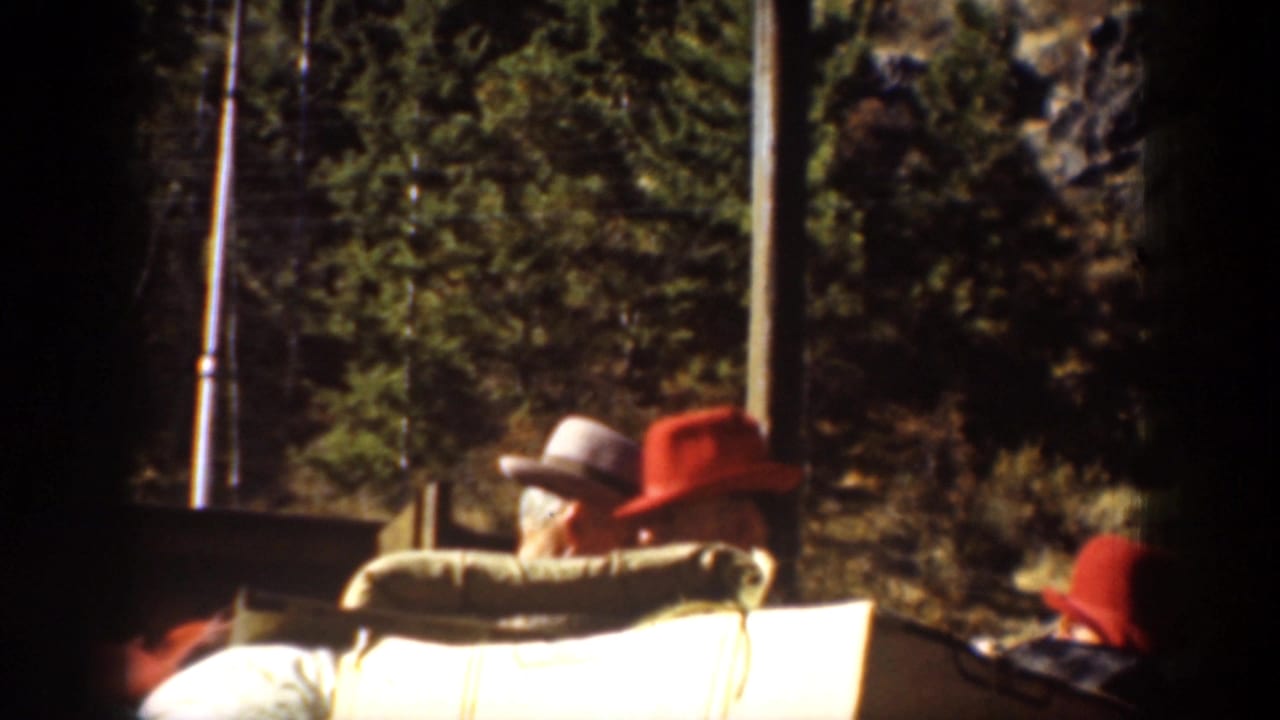 Passengers seated on a boat deck, including people in bright hats.