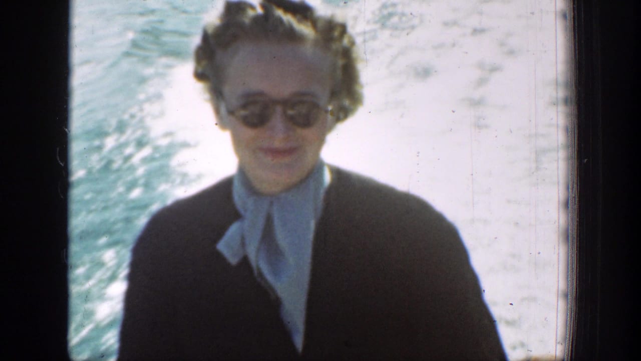 In Chelan, Washington, a woman in round sunglasses and a light scarf smiles toward the camera from a boat, with bright lake water behind her.