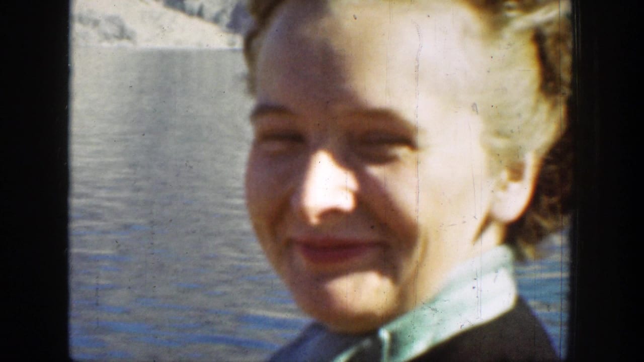 Close-up of the female tourist smiling beside the lake in Chelan, Washington, with soft focus and faded color from 8mm film.