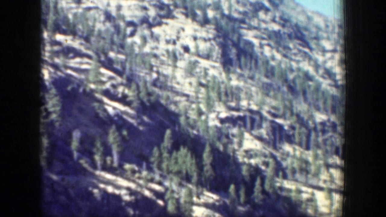 A wooded mountain slope rises above the lake near Chelan, Washington, captured in faded blue-green 8mm color.