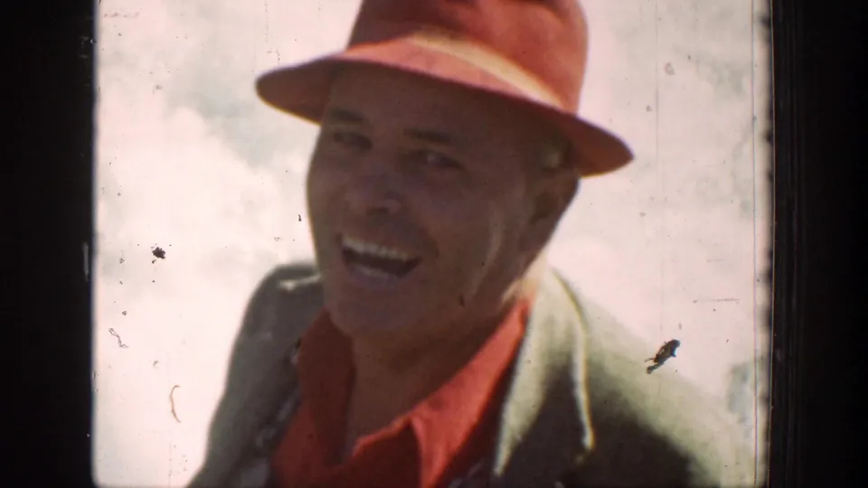 A man in a red fedora and jacket smiles toward the camera during a 1939 Chelan, Washington mountain journey.