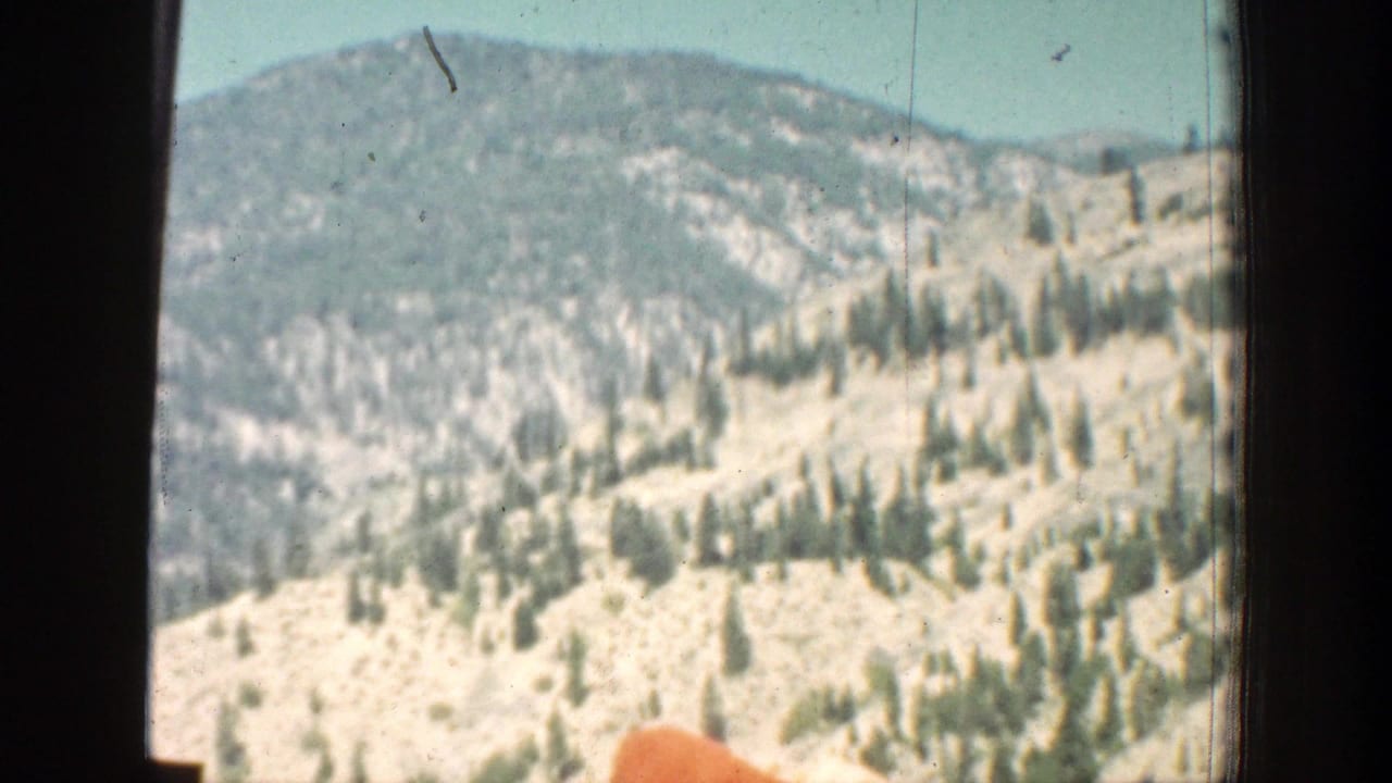 Wooded hills and pale rocky slopes appear through the vehicle window in the Chelan, Washington travel footage.