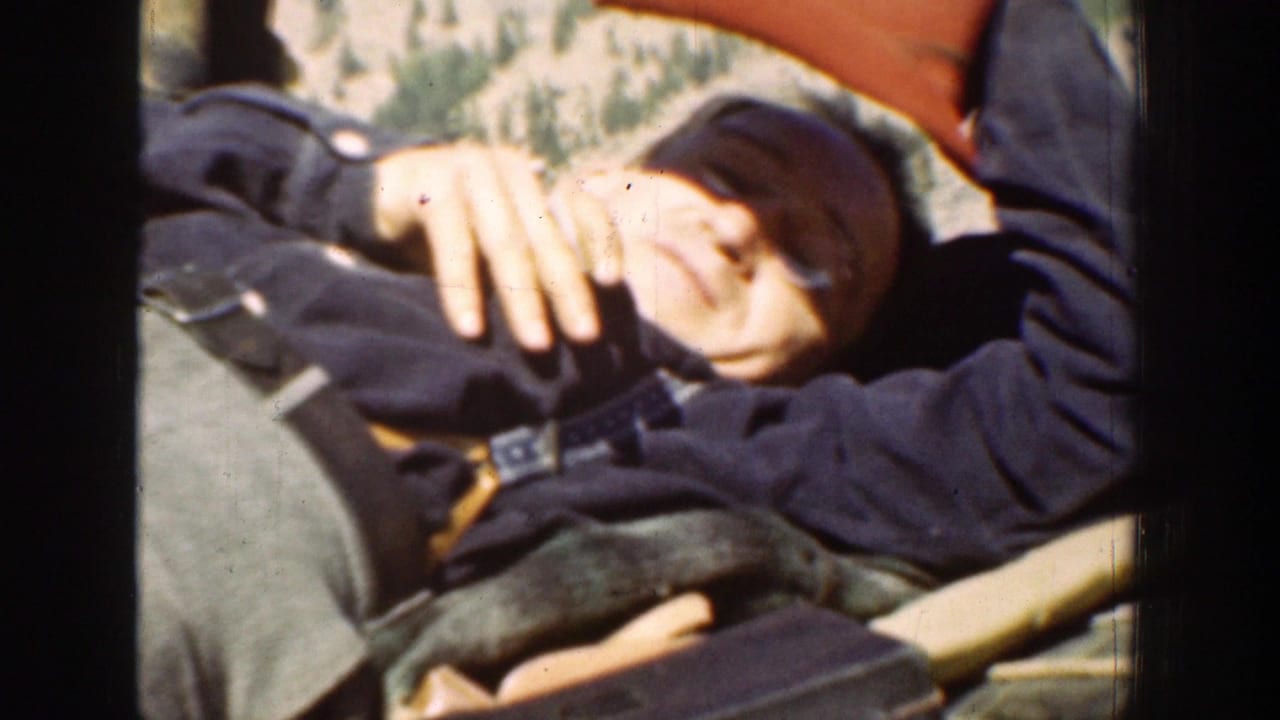 A passenger reclines inside the vehicle while another traveler in red clothing is partly visible behind him in the 1939 home movie.