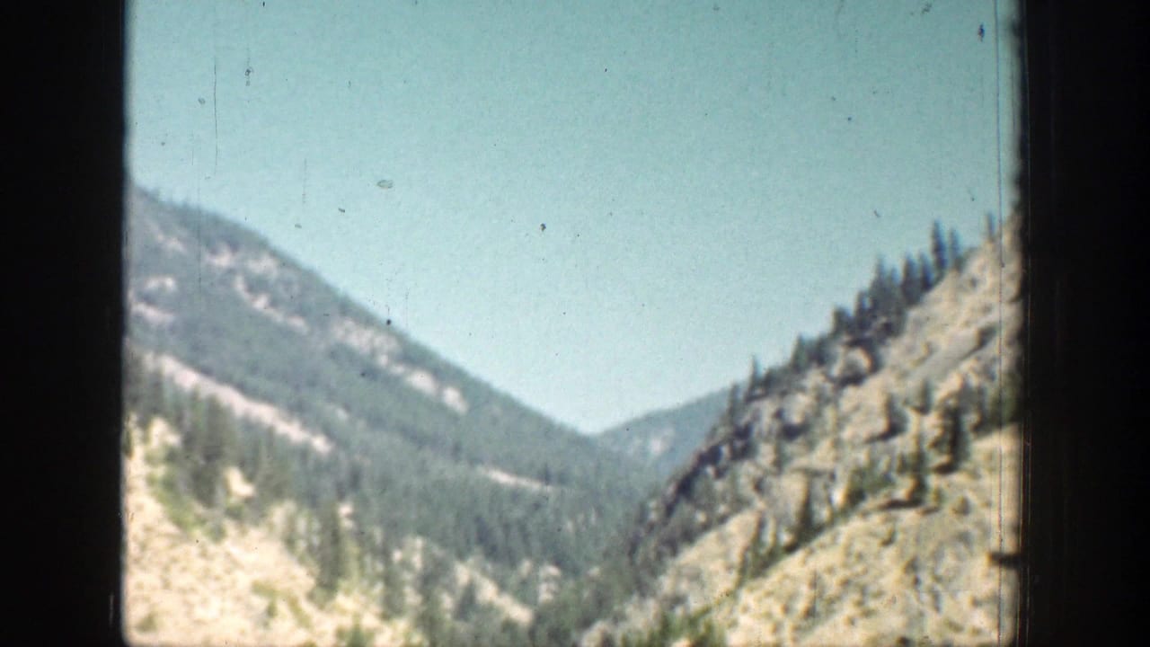 A rocky, wooded mountain valley is filmed through the vehicle window during the Chelan, Washington journey.