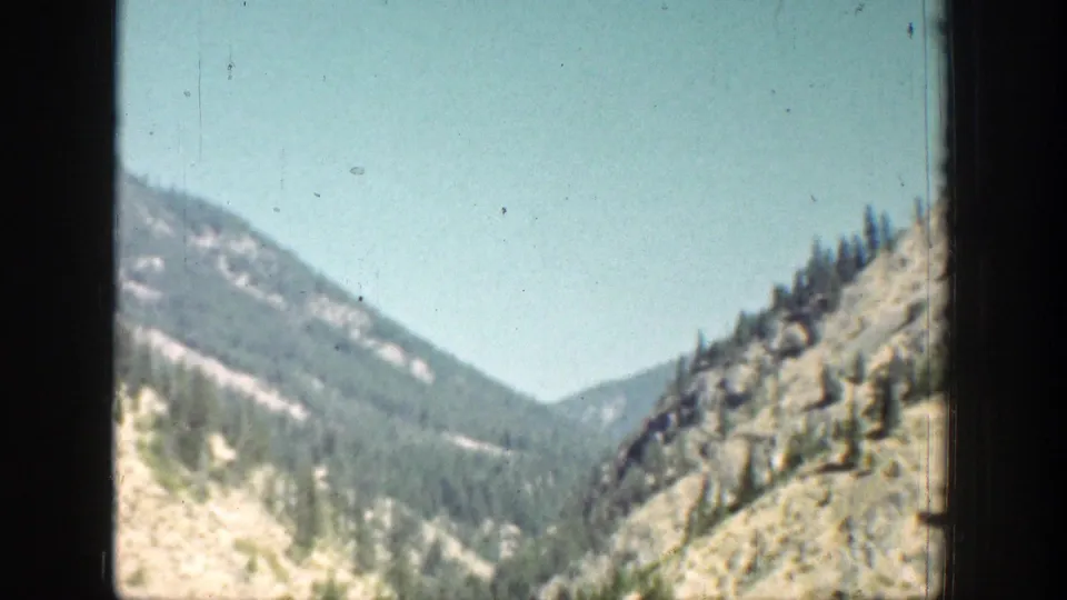 A rocky, wooded mountain valley is filmed through the vehicle window during the Chelan, Washington journey.