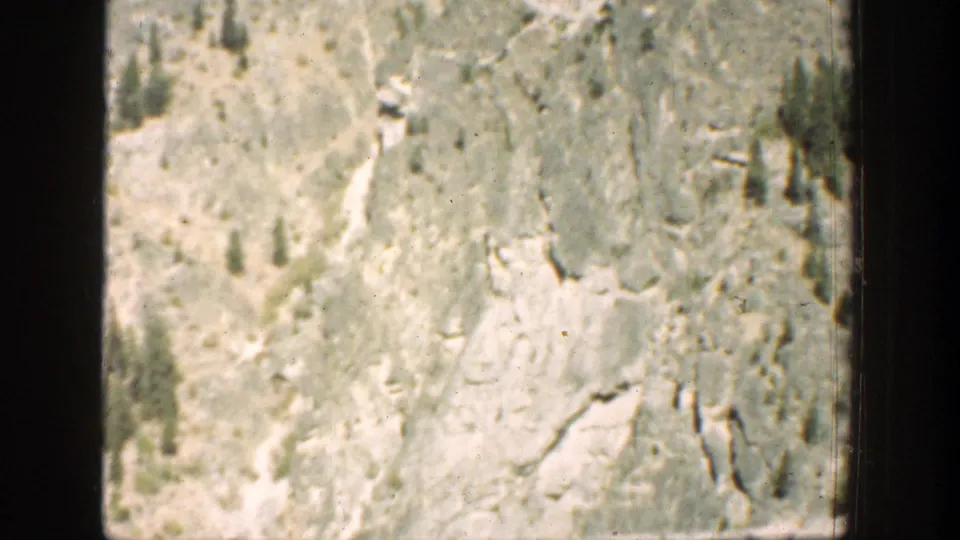 1939 Chelan, Washington 8mm frame showing a dry rocky slope with scattered pines and pale exposed rock.