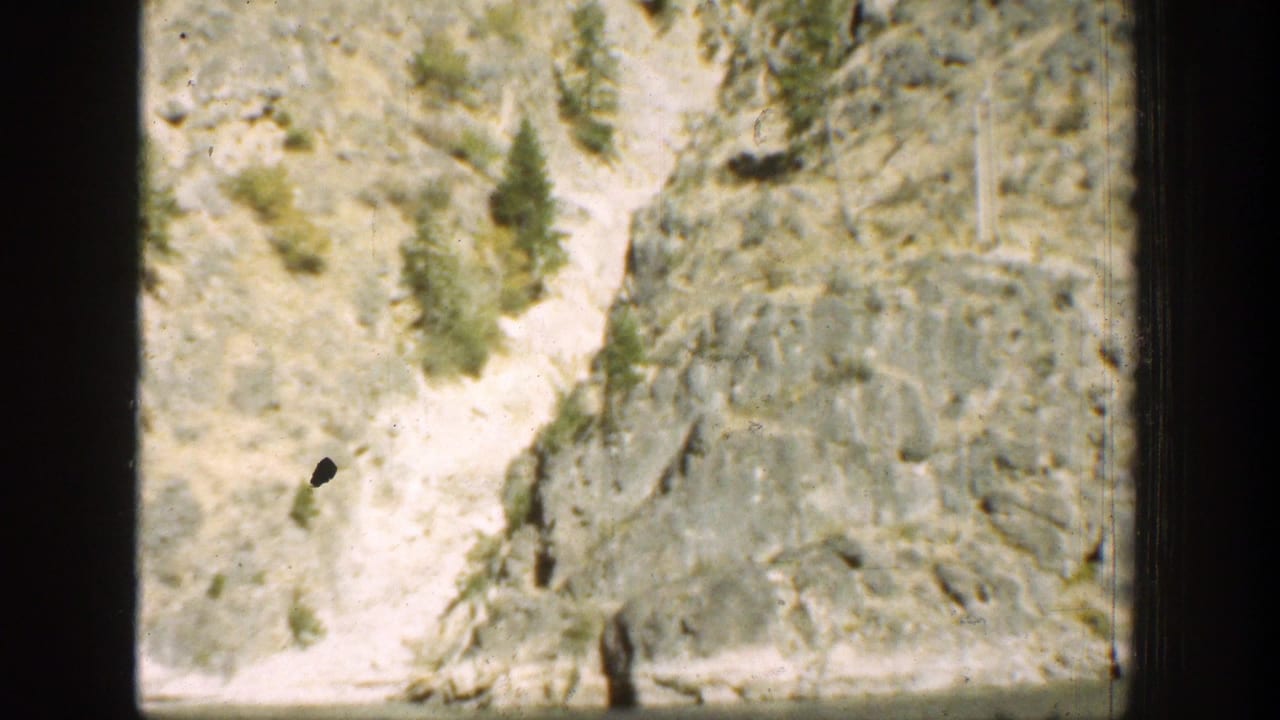 1939 Chelan, Washington view of a pale dry gully cutting through rocky mountain terrain with sparse trees.
