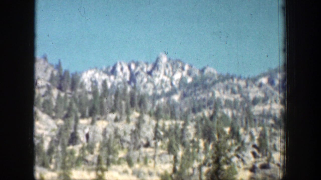 1939 Chelan, Washington landscape with a jagged distant ridge, scattered pines, dry slopes, and blue sky.