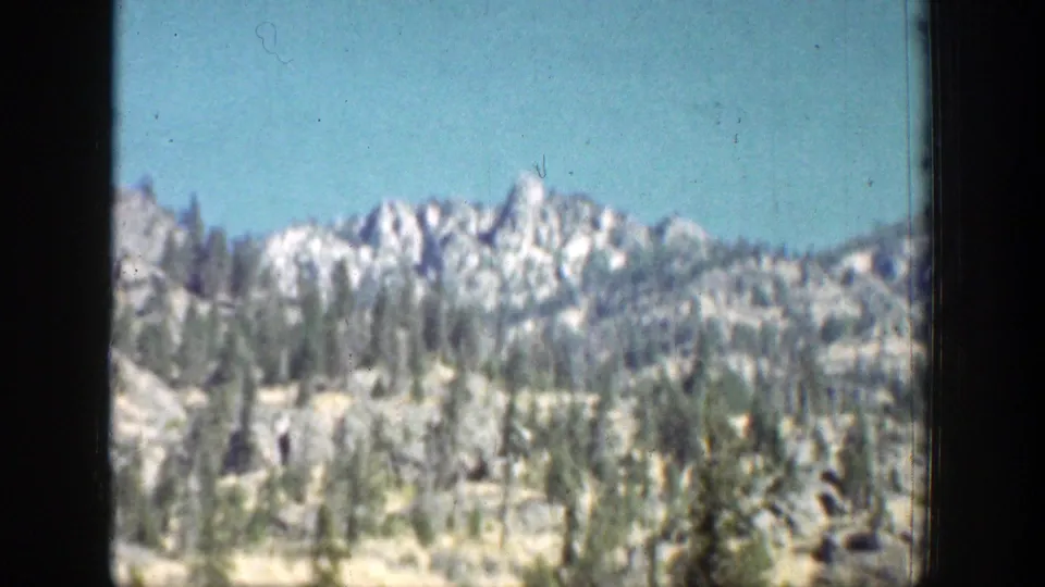 1939 Chelan, Washington landscape with a jagged distant ridge, scattered pines, dry slopes, and blue sky.