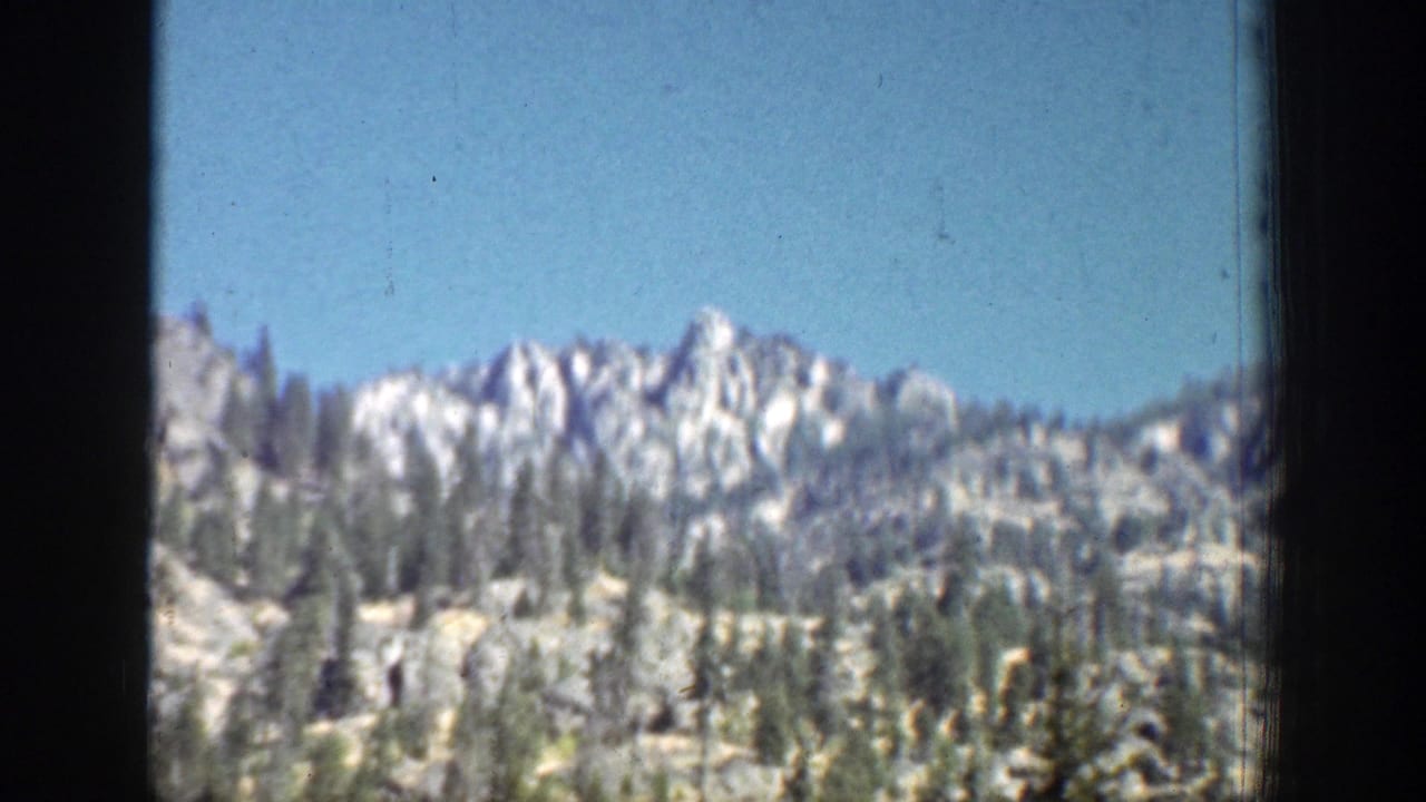 1939 Chelan, Washington travel footage showing a rocky mountain ridge and scattered evergreens from a moving viewpoint.