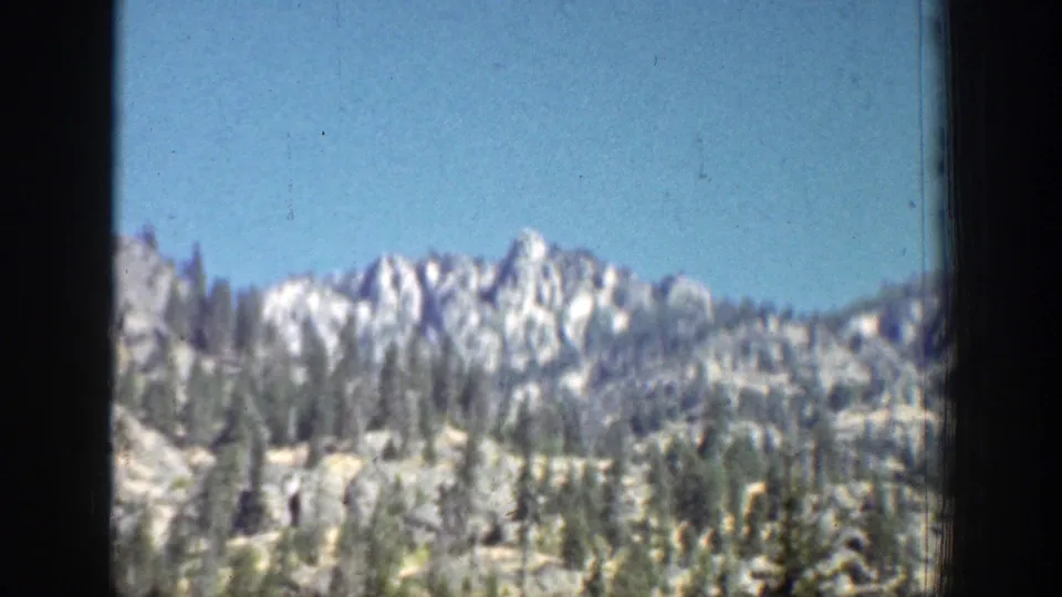 1939 Chelan, Washington travel footage showing a rocky mountain ridge and scattered evergreens from a moving viewpoint.