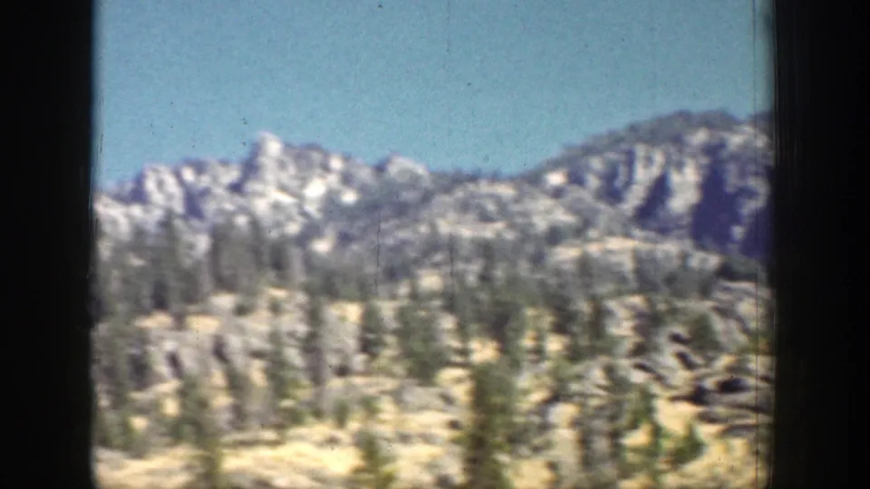 Chelan-area mountain ridges and evergreen forest are seen from a moving vehicle in 1939 8mm footage.