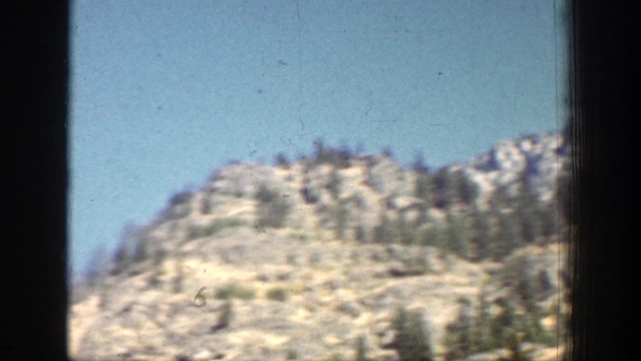 A sunlit rocky hill and scattered evergreens appear in the Chelan, Washington travel footage from 1939.