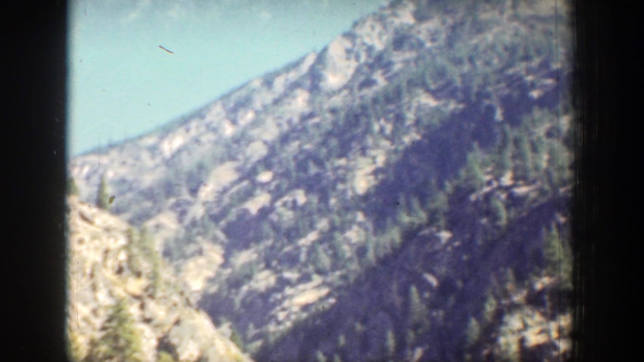 A soft 8mm view shows a pale rocky mountain face with scattered trees in the Chelan, Washington travel footage.