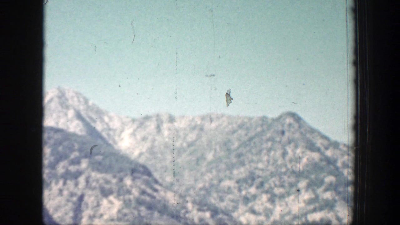 1939 Chelan-area 8mm view of a pale mountain ridge with snow traces and a dark frame edge in front.