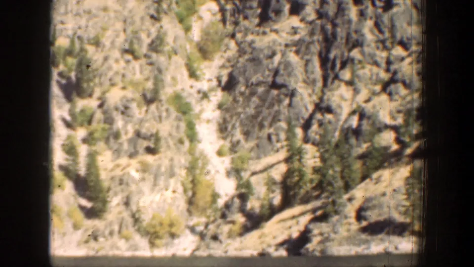 1939 Chelan, Washington 8mm frame showing a rugged rocky slope with evergreens and pale trail-like ground.
