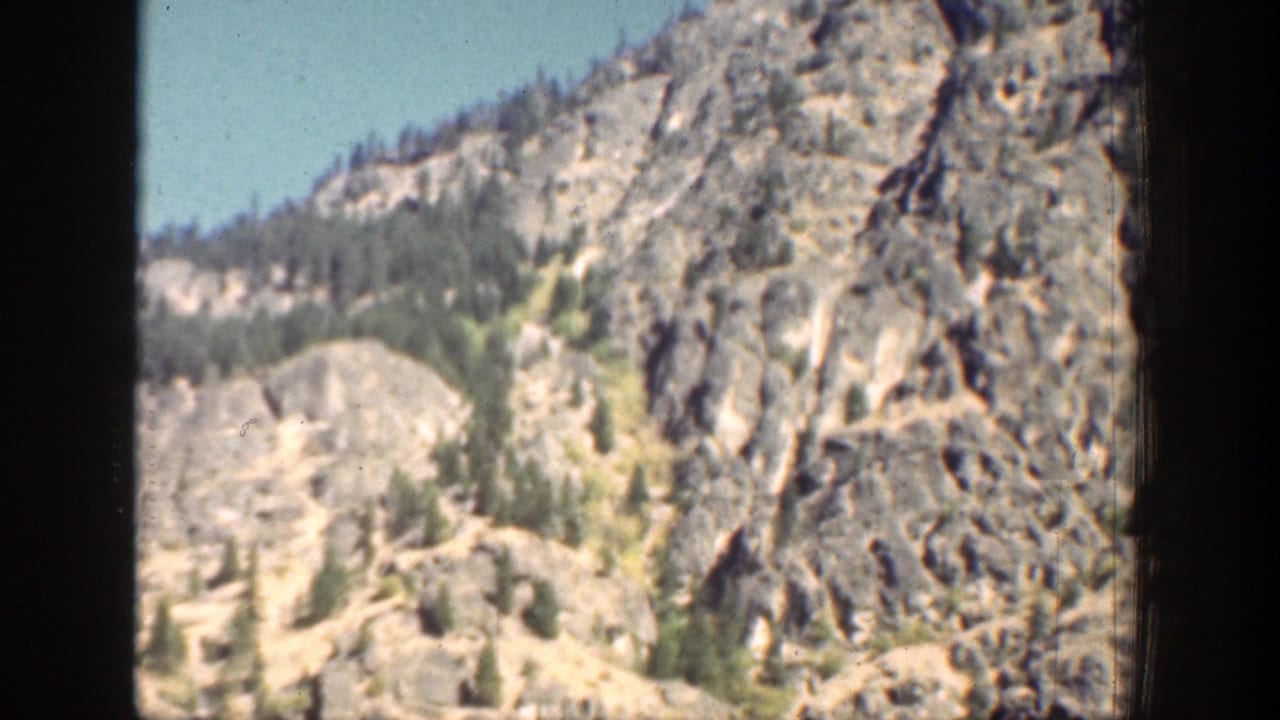 1939 Chelan, Washington home-movie view of steep rock walls, wooded slopes, and clear blue sky.