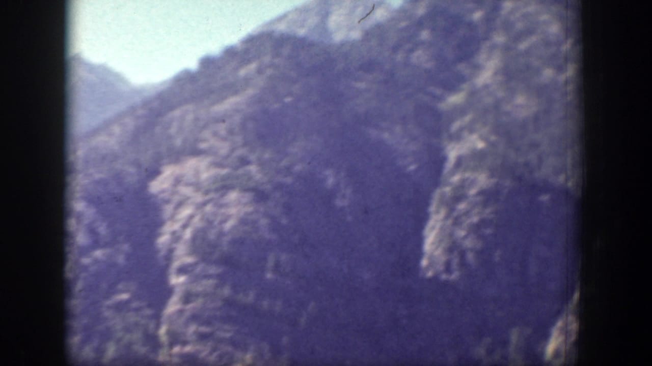 1939 Chelan, Washington frame with shadowed rocky slopes and a narrow mountain valley in soft, faded color.