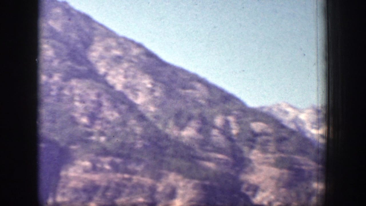 A steep mountain slope fills the frame with sky above and film borders at the sides.