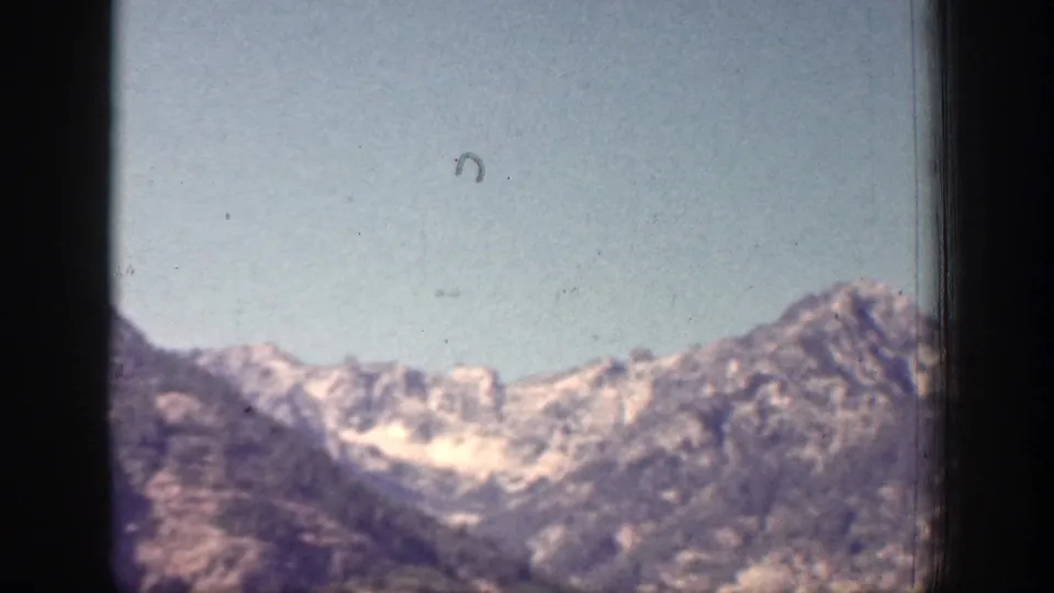 Snow-dusted ridgeline near Chelan, Washington, seen through worn 1939 8mm film with visible grain and edge framing.