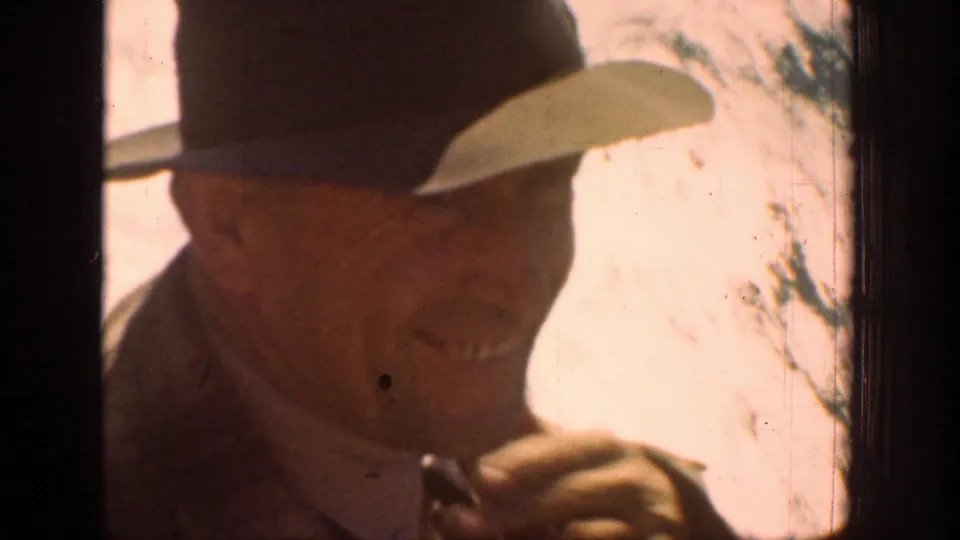 Adult man in a dark brimmed hat and jacket rides through the Chelan mountain area in 1939 home-movie footage.