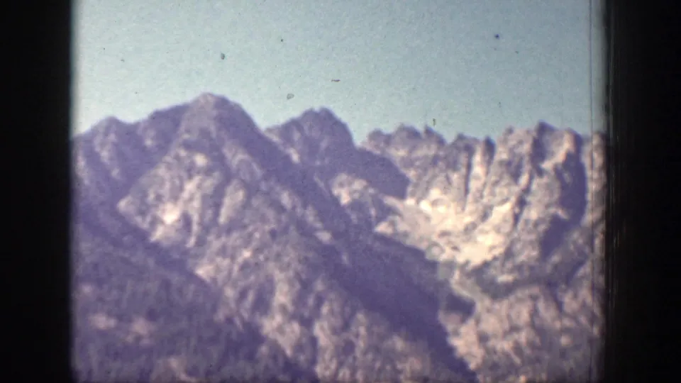 1939 Chelan, Washington frame with distant mountain peaks, rocky faces, and a hazy blue sky seen through 8mm film borders.