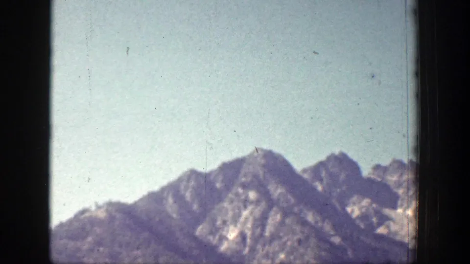 1939 Chelan, Washington frame showing mountain peaks, rocky ridgelines, and light haze within the borders of the 8mm film image.