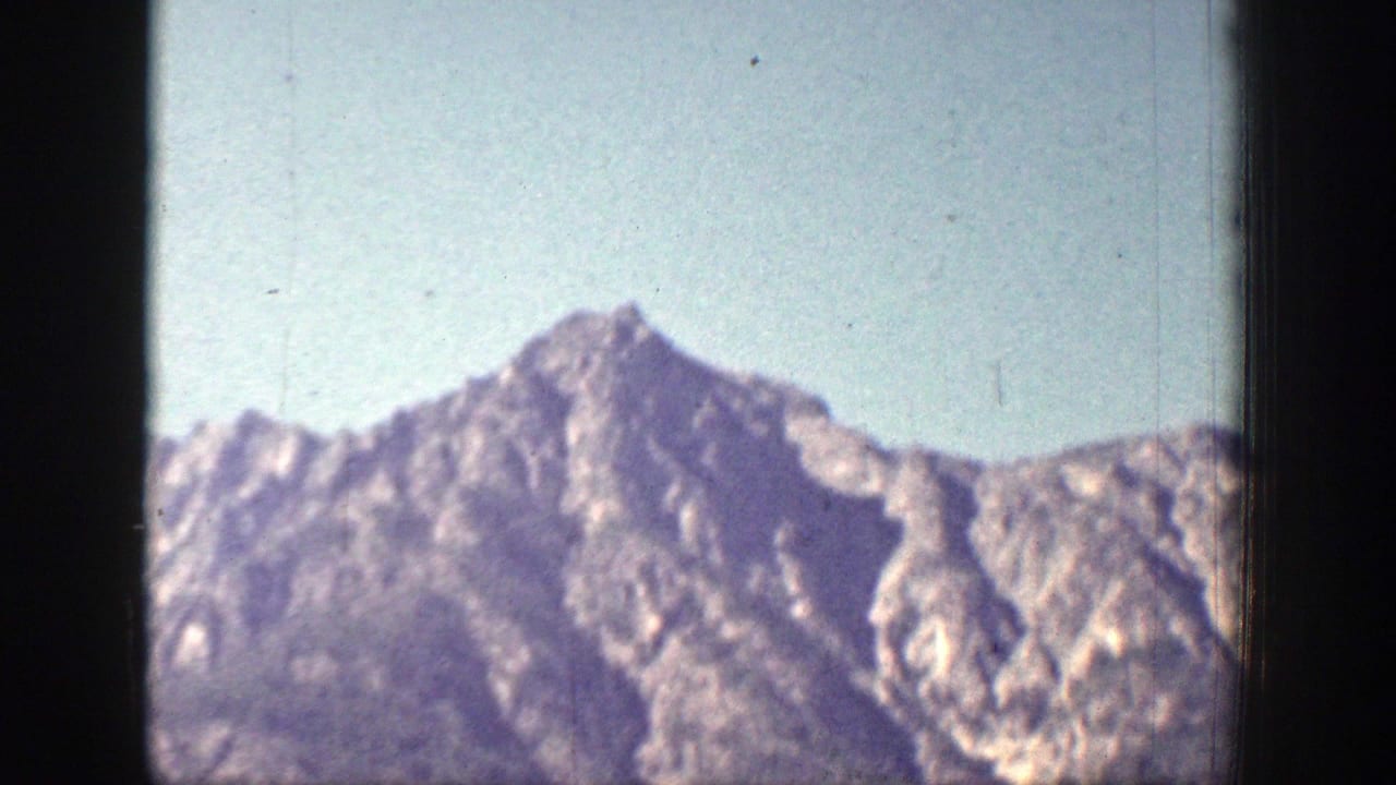 Soft, hazy mountain peaks beneath a pale sky with dark 8mm frame edges.