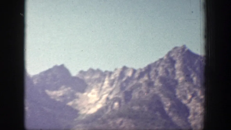 Chelan-area mountain peaks appear in a soft 1939 8mm frame, with rocky ridges, haze, and visible film gate edges.