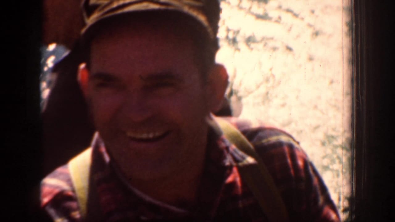 A smiling adult hiker appears briefly in the 1939 Chelan, Washington home movie, wearing a cap and plaid shirt near bright rock.