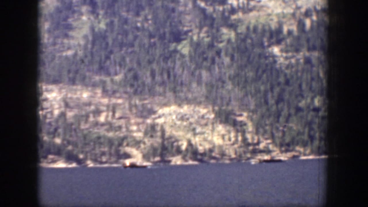 1939 Chelan, Washington frame of lake water and a distant forested shoreline viewed through visible 8mm gate borders.