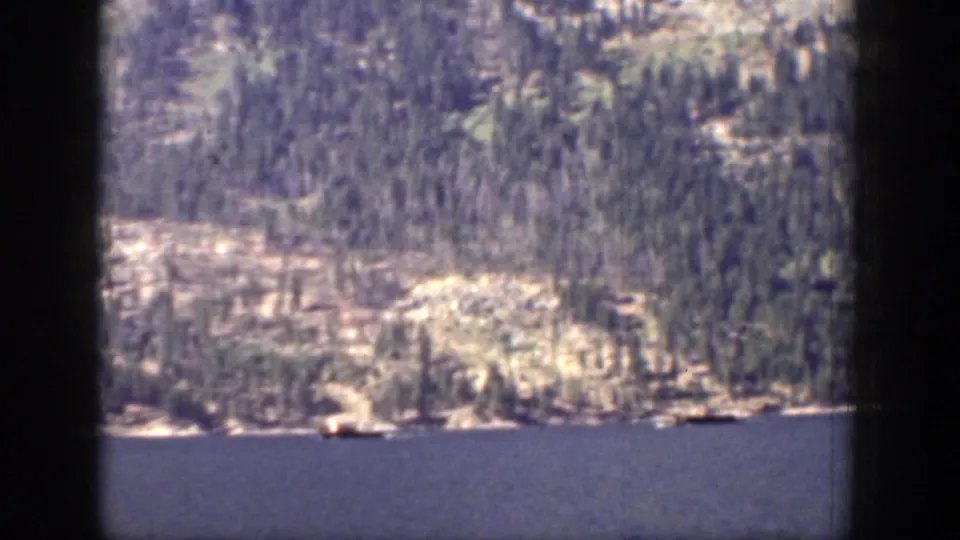 1939 Chelan, Washington frame of lake water and a distant forested shoreline viewed through visible 8mm gate borders.