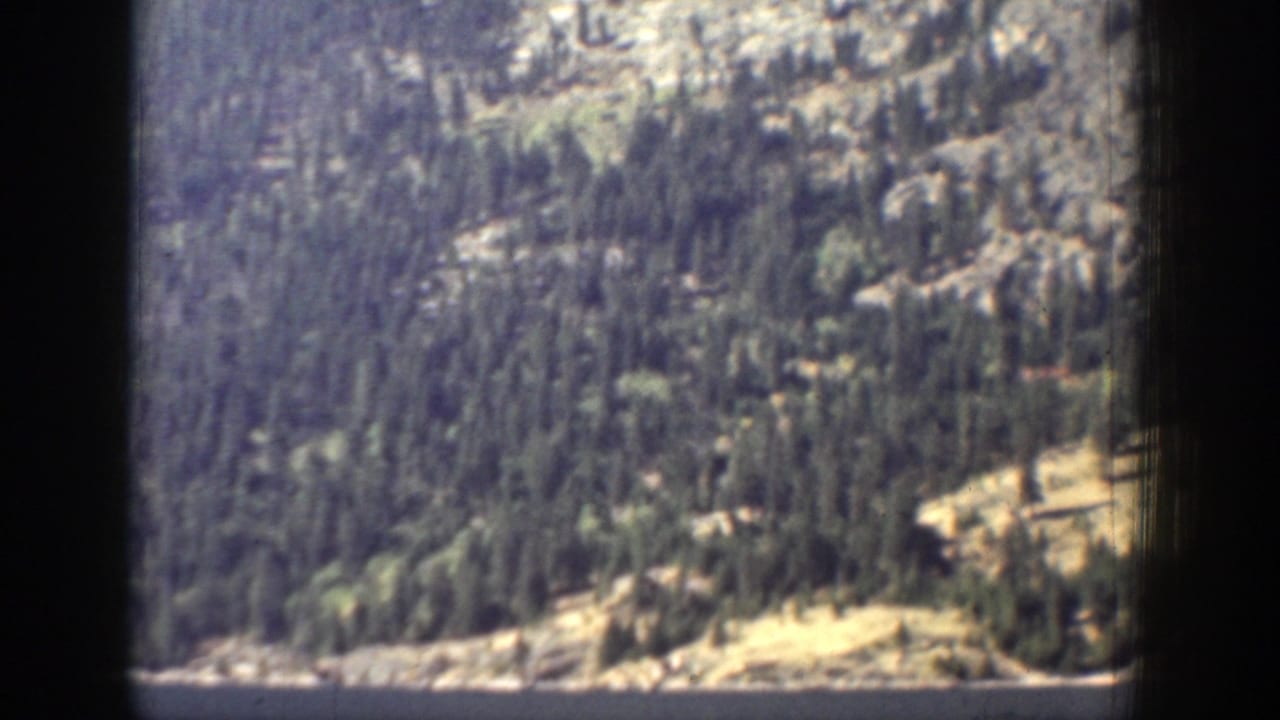 Chelan-area mountain landscape with evergreen forest, exposed rock, and faded 8mm color from the 1939 home movie.