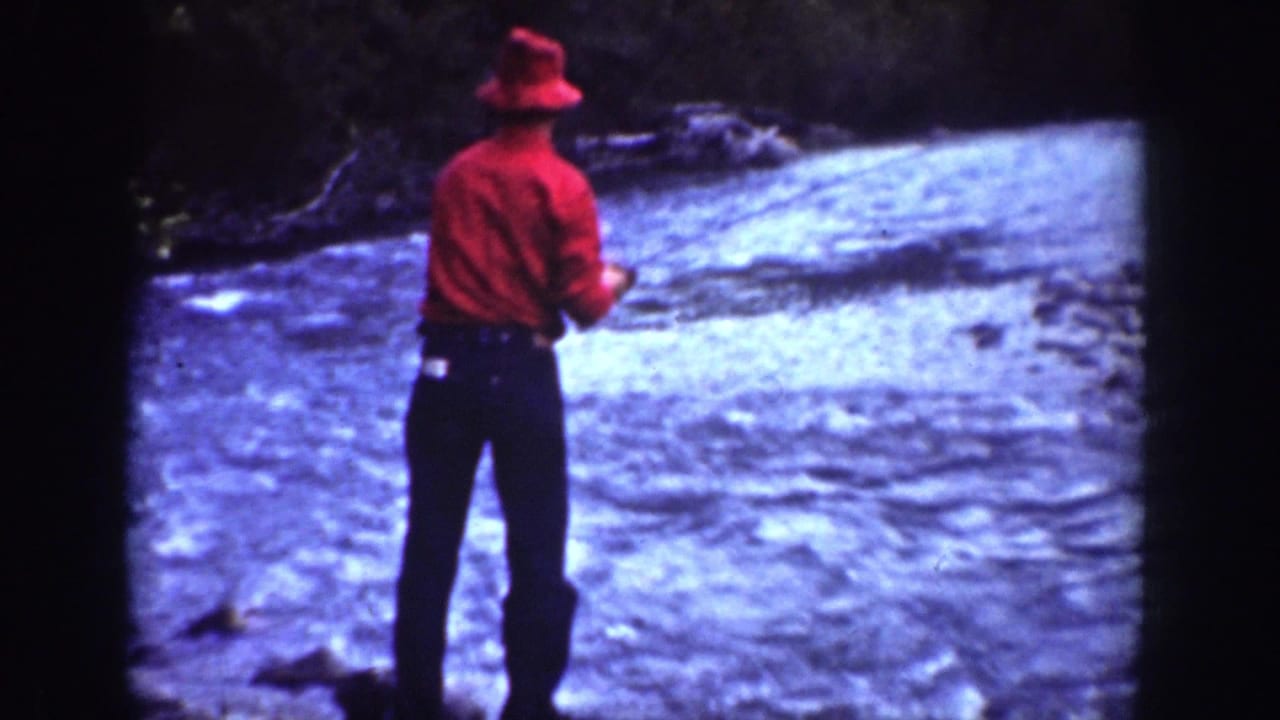In 1939 Chelan, Washington footage, a man in red clothing stands in rapid water with a fishing rod.