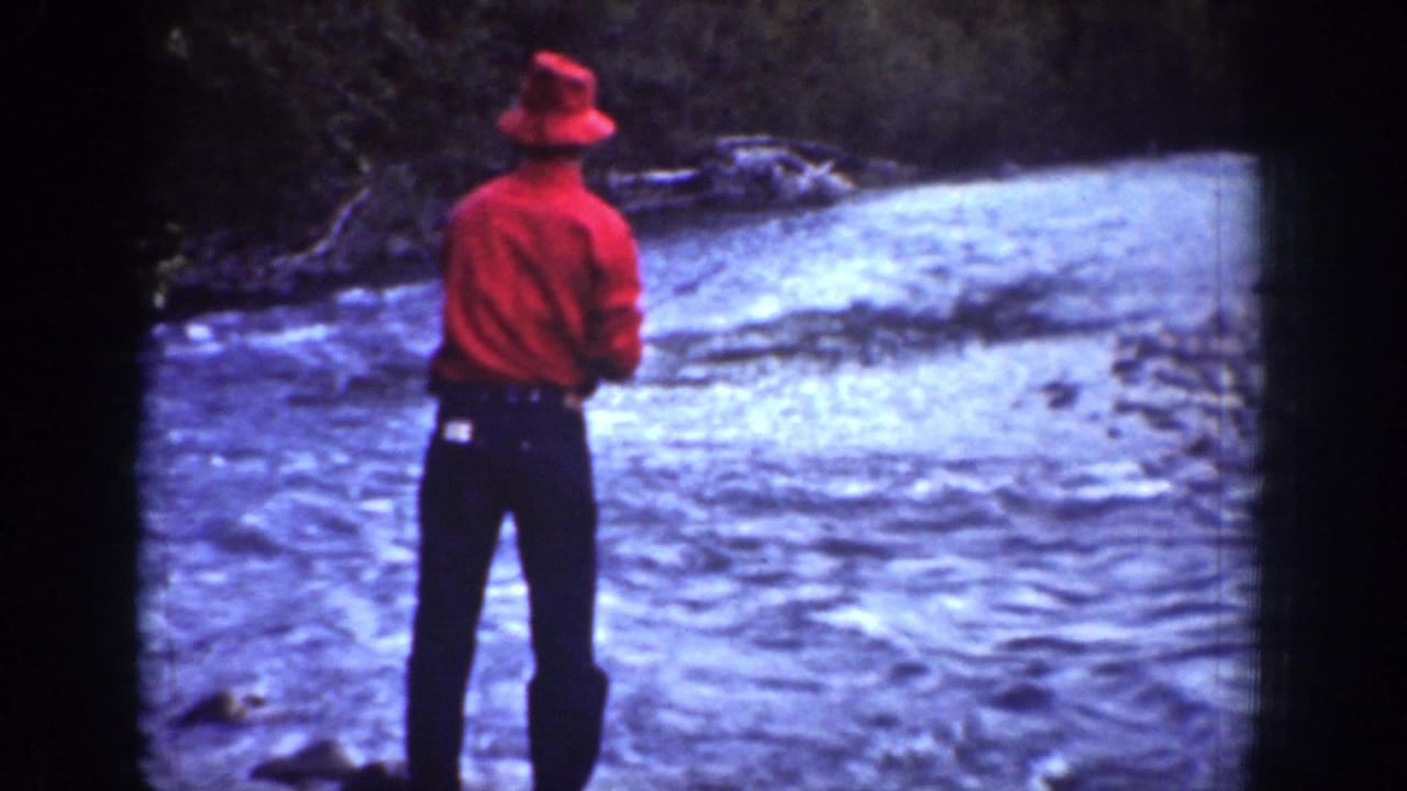 1939 Chelan, Washington 8mm frame of a lone angler in red standing near rapid river water.