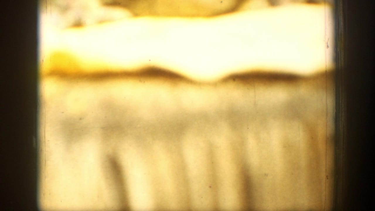 Soft 1939 8mm frame from Chelan, Washington, showing a curled yellowed paper edge on a textured tablecloth.