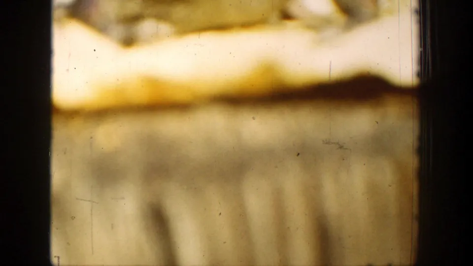 A close 1939 home-movie view of curled yellow paper and tablecloth texture, with visible film wear and soft focus.