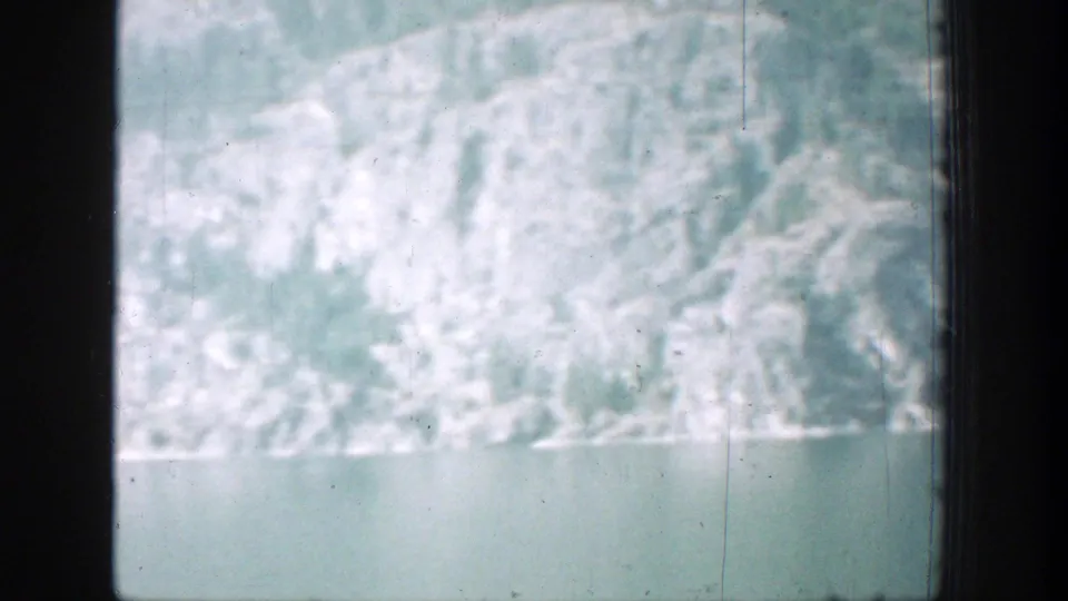 1939 home-movie view of Lake Chelan scenery with snowy slopes, lake water, and heavy window framing.