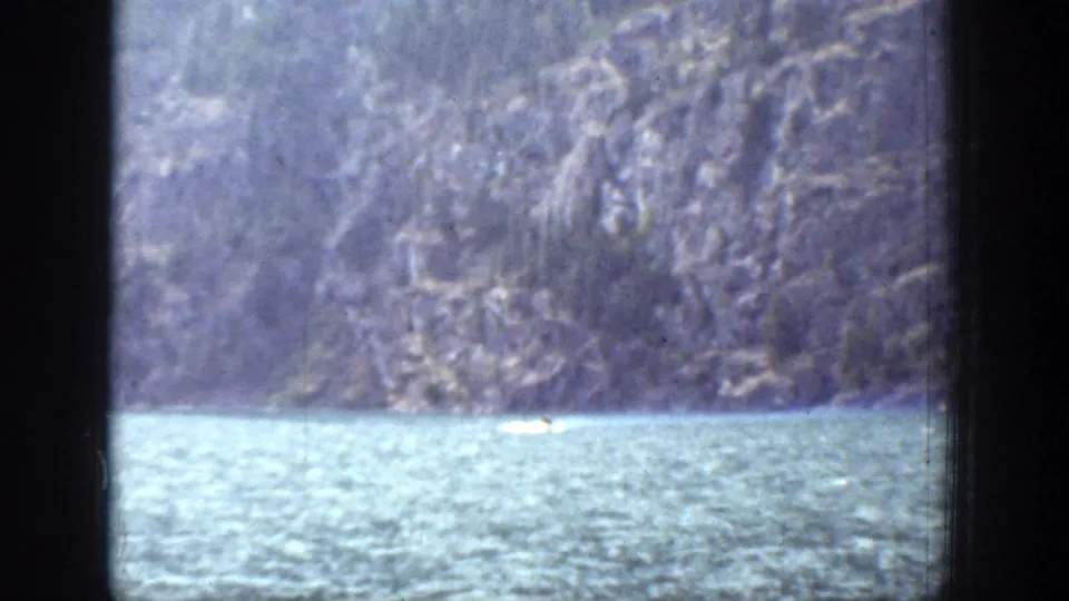 A distant boat travels across Lake Chelan water in a 1939 home-movie frame with dark vertical borders.