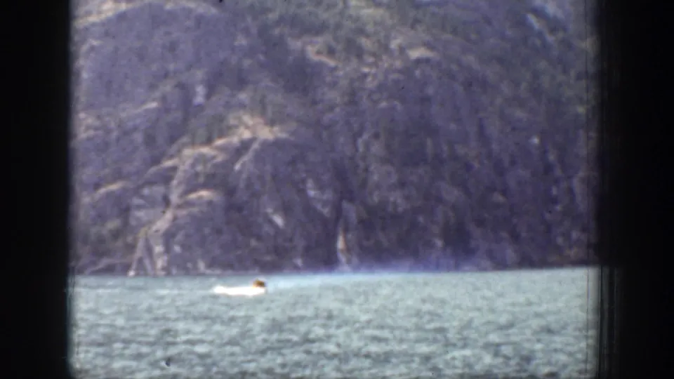 A small boat continues across Chelan, Washington lake water in a faded 1939 8mm home-movie frame.