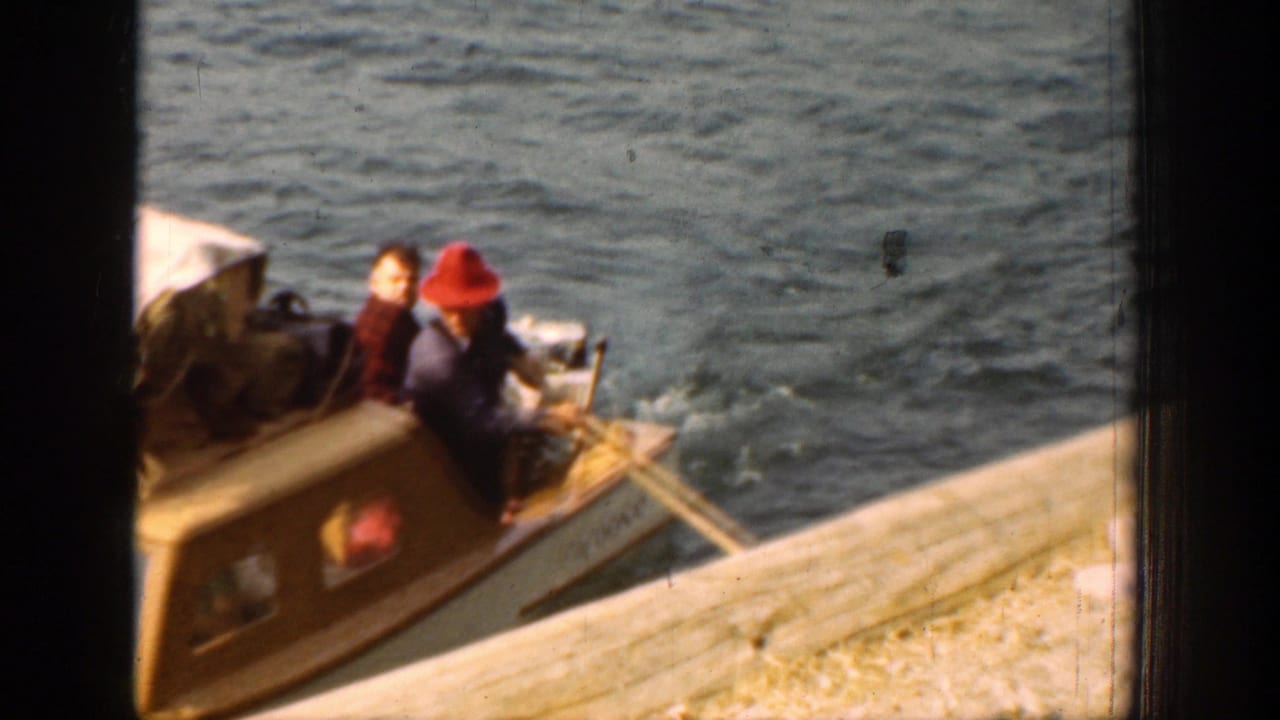 Near the dock at Lake Chelan, passengers sit aboard the small boat as lines or oars extend toward the pier edge.