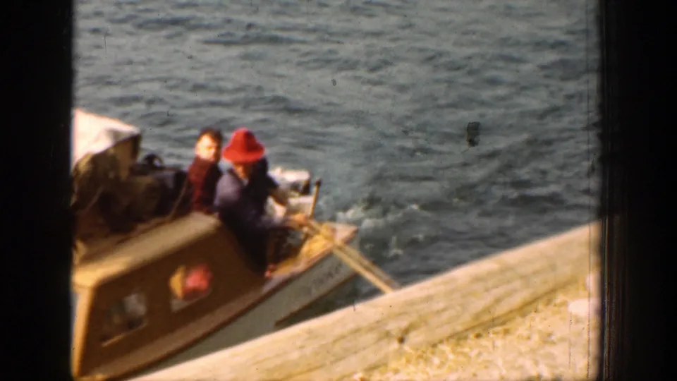Near the dock at Lake Chelan, passengers sit aboard the small boat as lines or oars extend toward the pier edge.