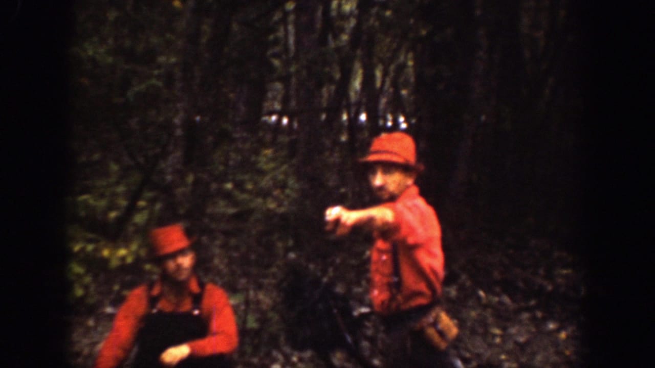 Two men in red shirts and hats stand among trees in the 1939 Chelan, Washington footage, with one man pointing toward the camera or path.