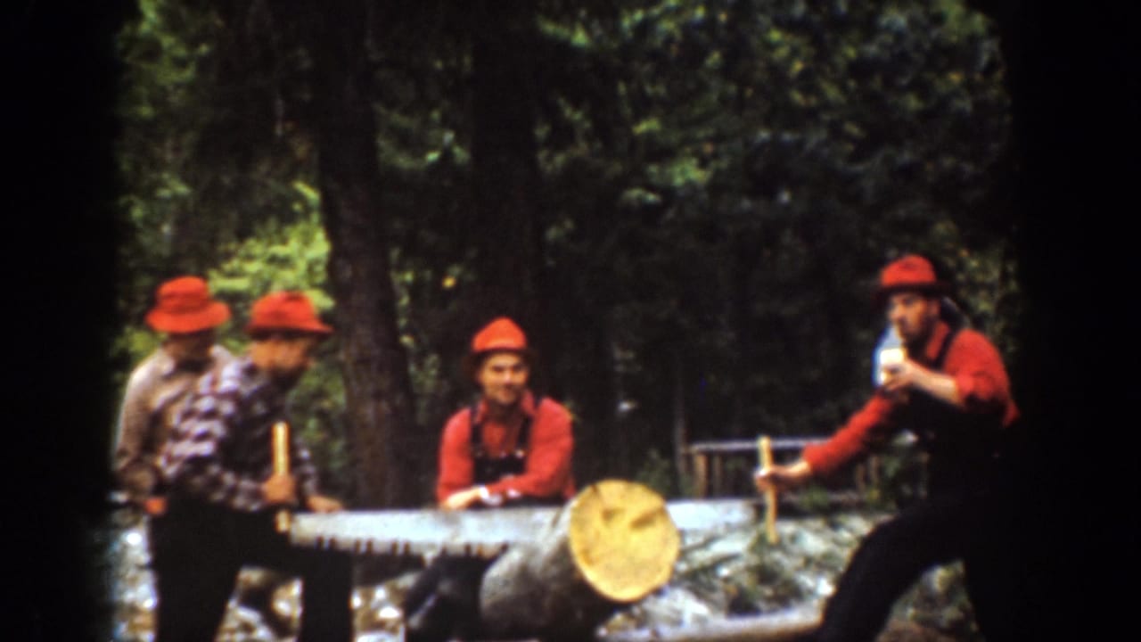 Men in red hats gather around a large log with a crosscut saw in a wooded area.